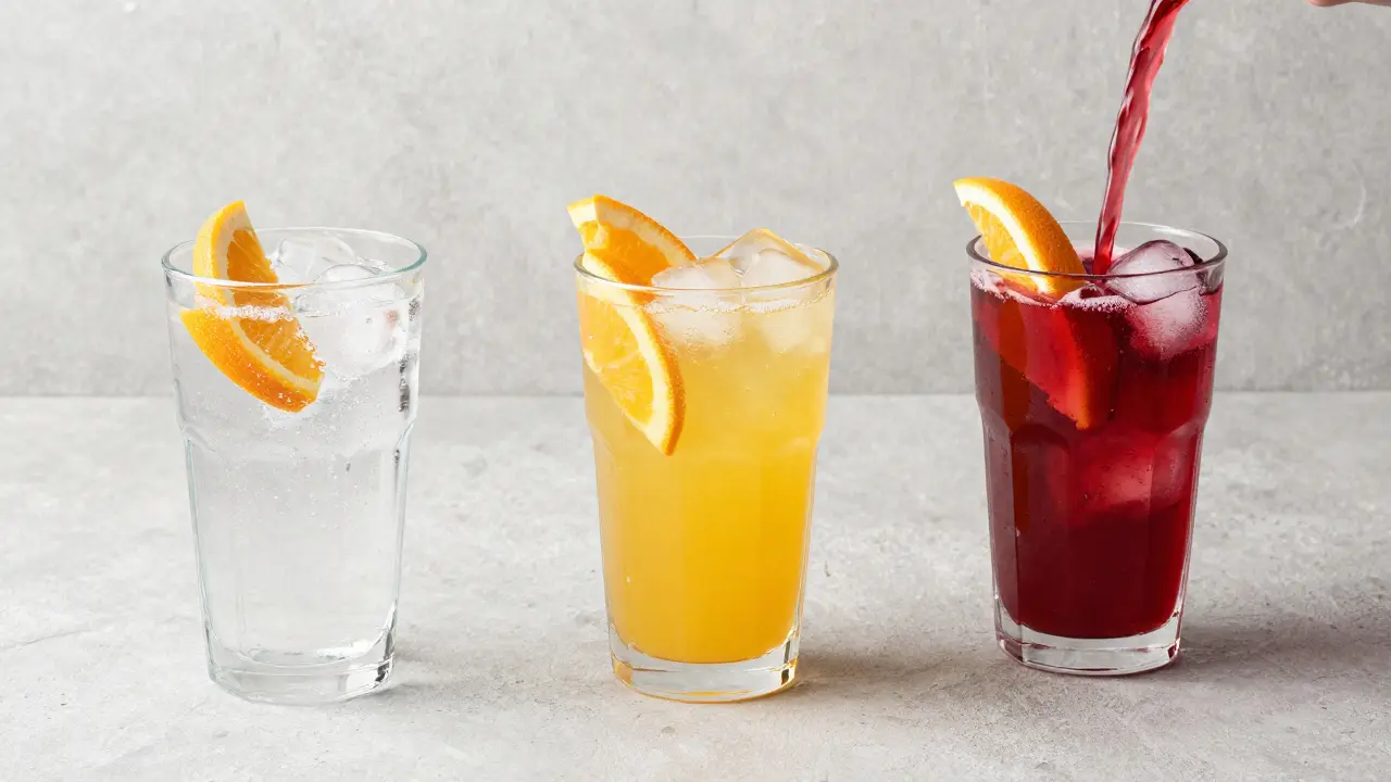 Drei verschiedene CBD-Getränke in Gläsern mit Eis und Früchten aus der Vogelperspektive.